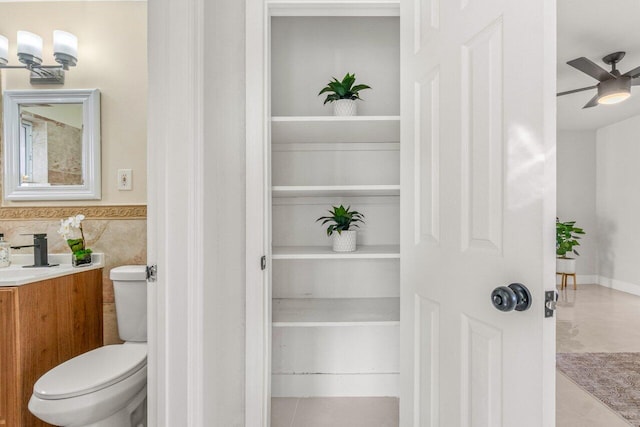 bathroom with tile patterned floors, vanity, tile walls, toilet, and ceiling fan