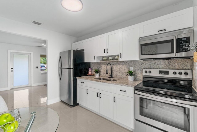 kitchen with white cabinets, appliances with stainless steel finishes, sink, and light stone counters