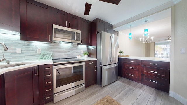 kitchen with appliances with stainless steel finishes, ornamental molding, pendant lighting, sink, and tasteful backsplash