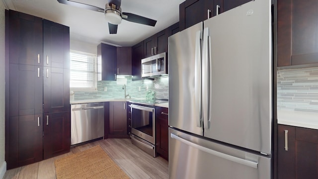 kitchen featuring light hardwood / wood-style floors, decorative backsplash, appliances with stainless steel finishes, ceiling fan, and sink