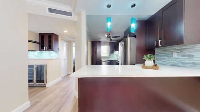 kitchen with kitchen peninsula, hanging light fixtures, backsplash, stainless steel refrigerator, and ceiling fan