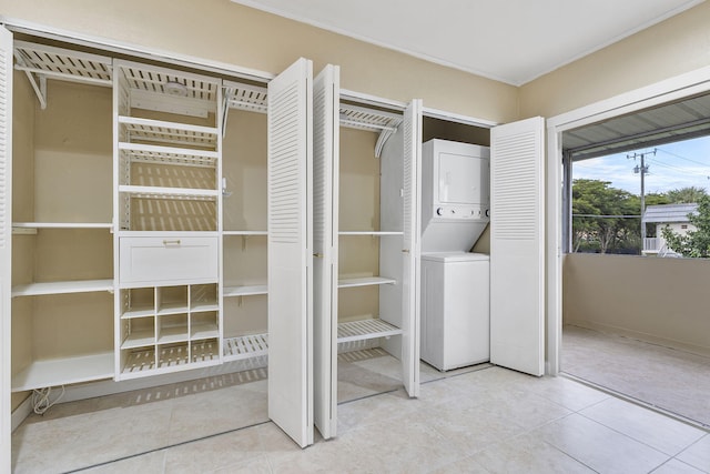 laundry area with light tile patterned floors and stacked washer and clothes dryer