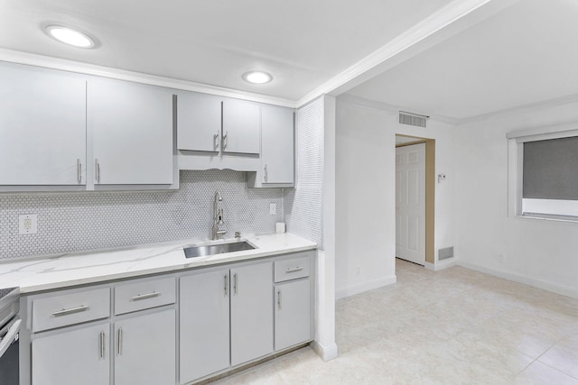 kitchen featuring light stone counters, tasteful backsplash, crown molding, gray cabinetry, and sink