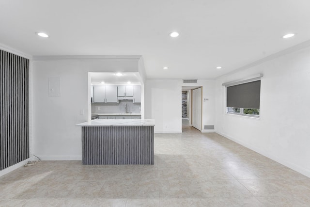 kitchen featuring crown molding, kitchen peninsula, light tile patterned floors, sink, and backsplash