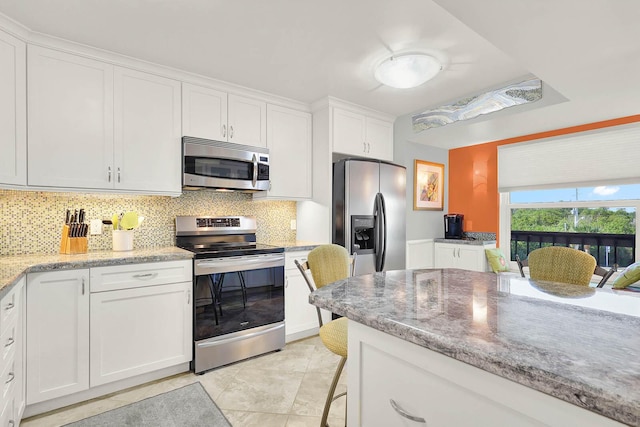 kitchen with decorative backsplash, appliances with stainless steel finishes, light stone counters, and white cabinetry