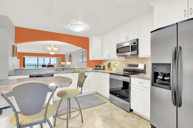 kitchen featuring tasteful backsplash, kitchen peninsula, light stone countertops, stainless steel appliances, and white cabinets