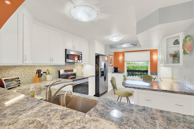 kitchen featuring decorative backsplash, a kitchen bar, sink, stainless steel appliances, and white cabinets