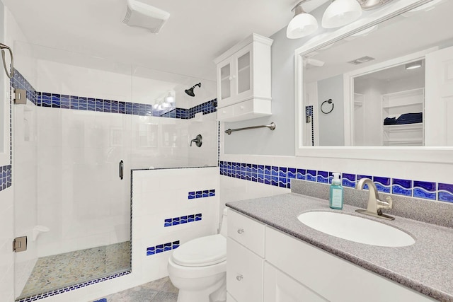 bathroom featuring toilet, a shower with shower door, tile patterned flooring, tile walls, and vanity