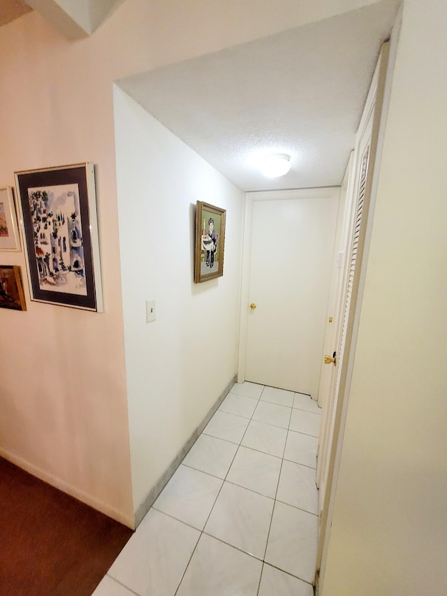 corridor with a textured ceiling and light tile patterned flooring