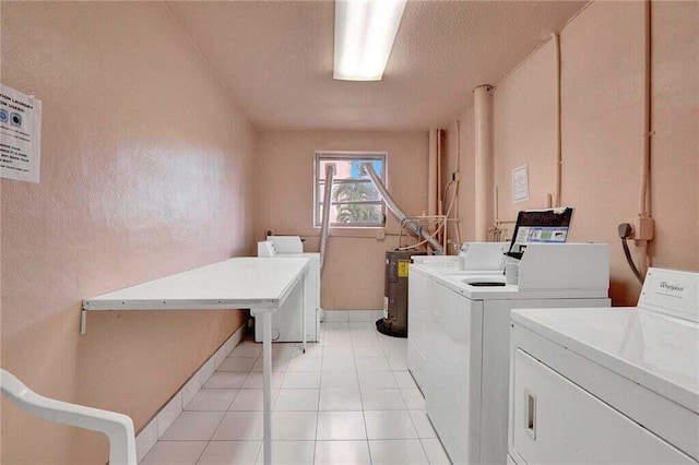 clothes washing area with light tile patterned flooring, washing machine and clothes dryer, and a textured ceiling