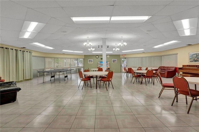 dining room with a drop ceiling, light tile patterned floors, and an inviting chandelier