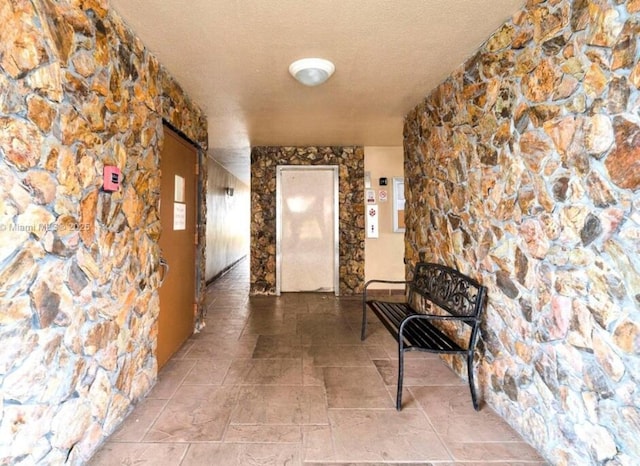 corridor with elevator and a textured ceiling