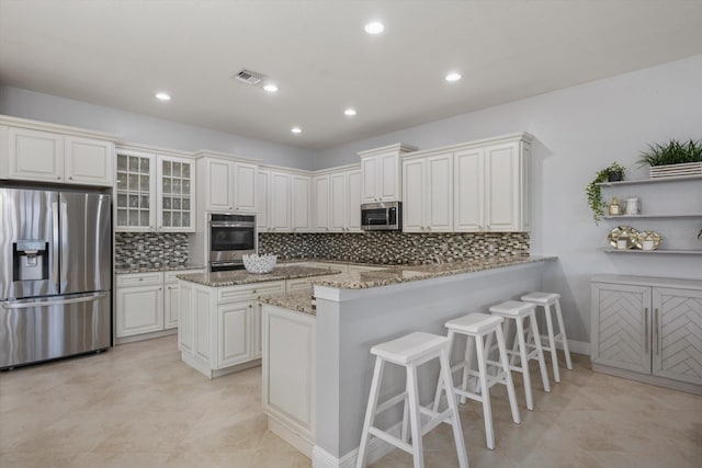 kitchen featuring light stone counters, stainless steel appliances, a center island, and white cabinets