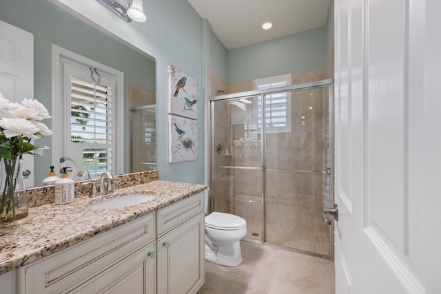 bathroom with tile patterned floors, vanity, toilet, and a shower with shower door