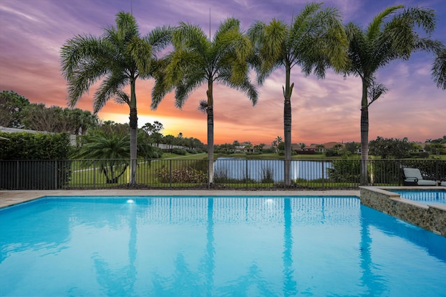 pool at dusk with a jacuzzi and a water view