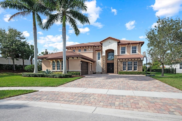 mediterranean / spanish home with a garage and a front lawn