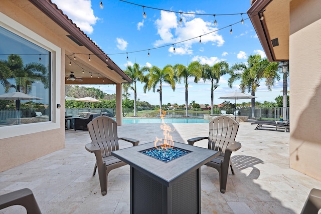 view of patio featuring a fenced in pool, a water view, ceiling fan, and an outdoor fire pit