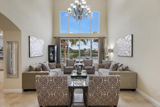 living room with a notable chandelier, light tile patterned floors, and a high ceiling