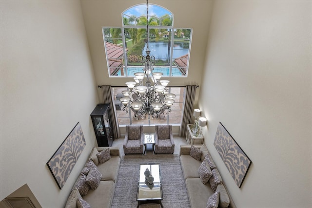 living room featuring a high ceiling, a water view, and a notable chandelier