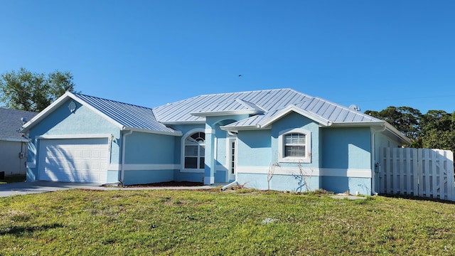 view of front of home with stucco siding, an attached garage, a standing seam roof, and fence