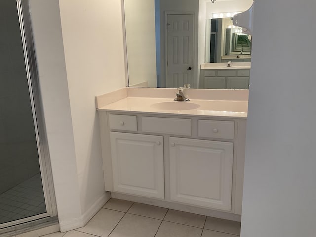 full bathroom with baseboards, a tile shower, vanity, and tile patterned flooring