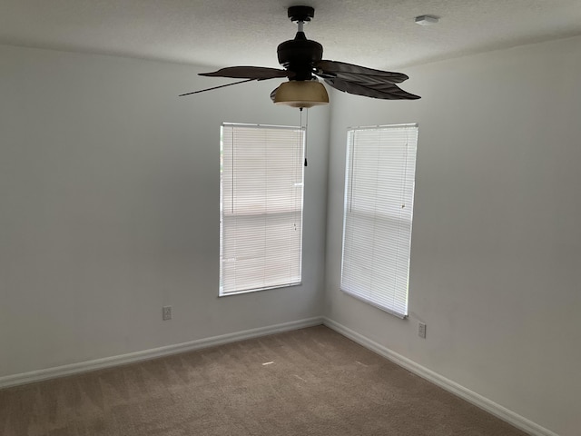 carpeted spare room with baseboards, a textured ceiling, and a ceiling fan