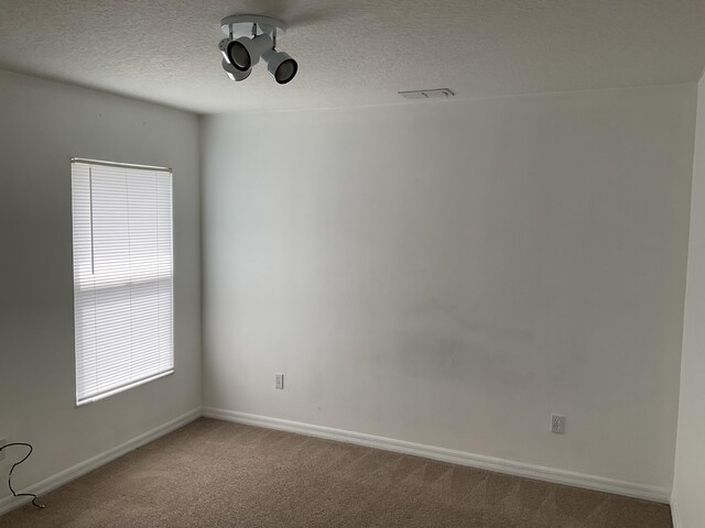 carpeted empty room featuring baseboards and a textured ceiling