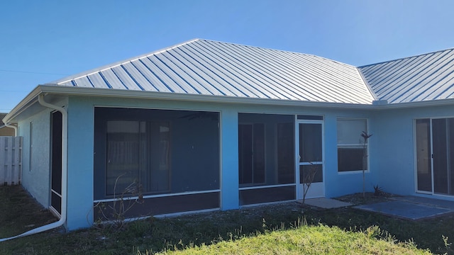 exterior space with stucco siding, a standing seam roof, and a sunroom