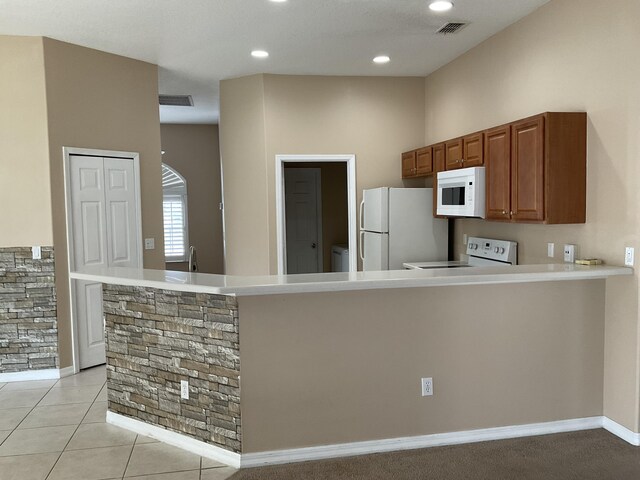 kitchen with white appliances, kitchen peninsula, and light tile patterned floors