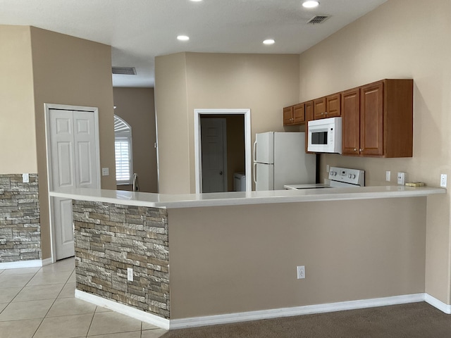 kitchen featuring white appliances, visible vents, a peninsula, light countertops, and brown cabinets