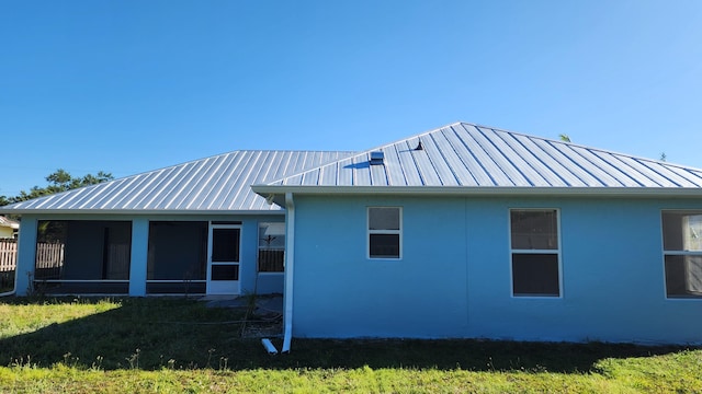 view of side of home with a standing seam roof, stucco siding, a sunroom, and metal roof