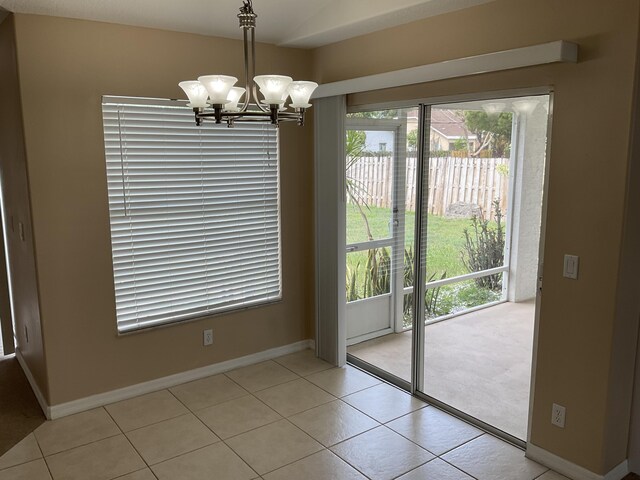 interior space featuring light tile patterned floors, baseboards, and an inviting chandelier