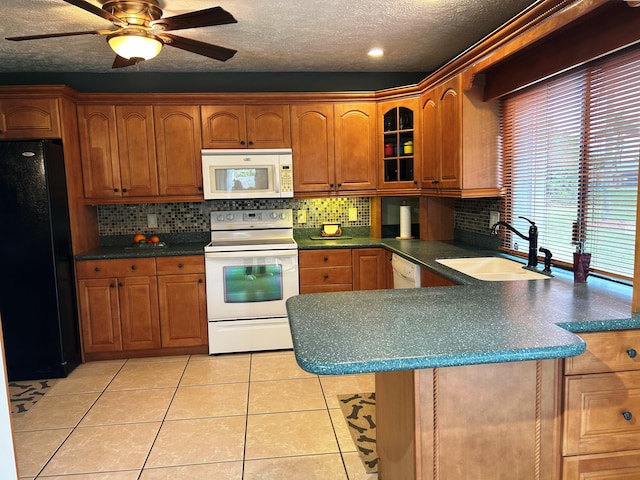 kitchen with sink, light tile patterned floors, kitchen peninsula, white appliances, and decorative backsplash