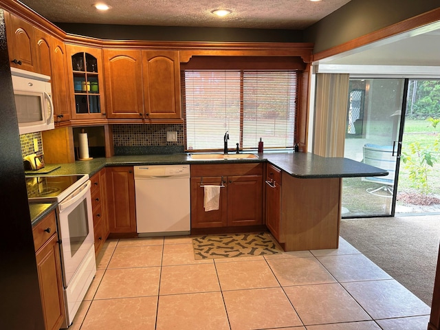 kitchen featuring sink, backsplash, light tile patterned floors, white appliances, and a textured ceiling