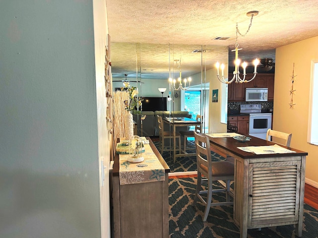 kitchen featuring decorative light fixtures, white electric stove, tasteful backsplash, a kitchen bar, and a textured ceiling