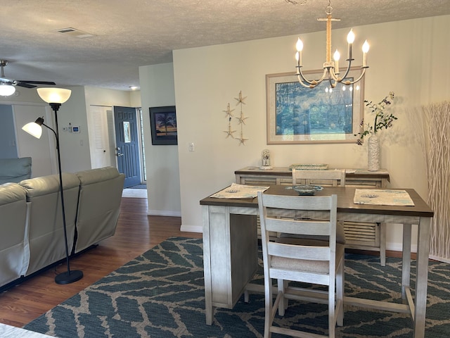 dining space with ceiling fan with notable chandelier, dark wood-type flooring, and a textured ceiling