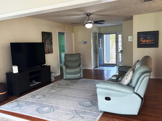 living room with ceiling fan, dark hardwood / wood-style floors, and a textured ceiling