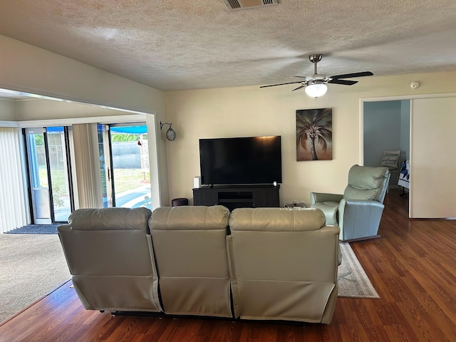 living room featuring dark hardwood / wood-style flooring, ceiling fan, and a textured ceiling