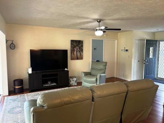 living room featuring ceiling fan, dark hardwood / wood-style floors, and a textured ceiling