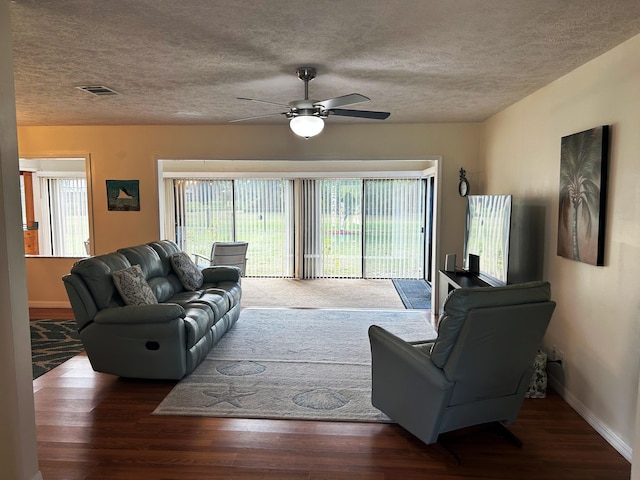 living room with wood-type flooring, ceiling fan, and a textured ceiling