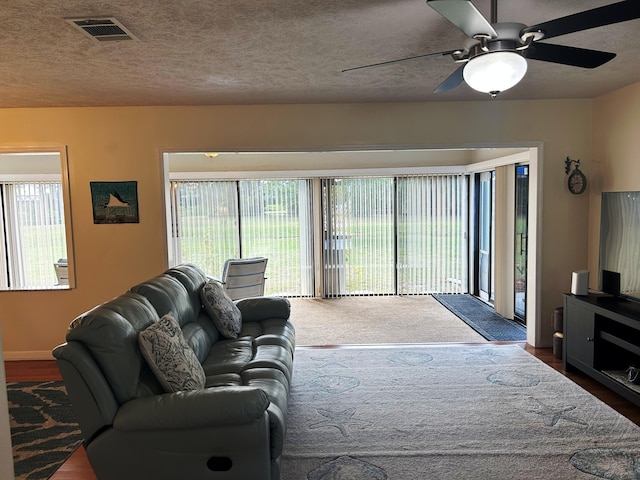 living room featuring ceiling fan and a textured ceiling