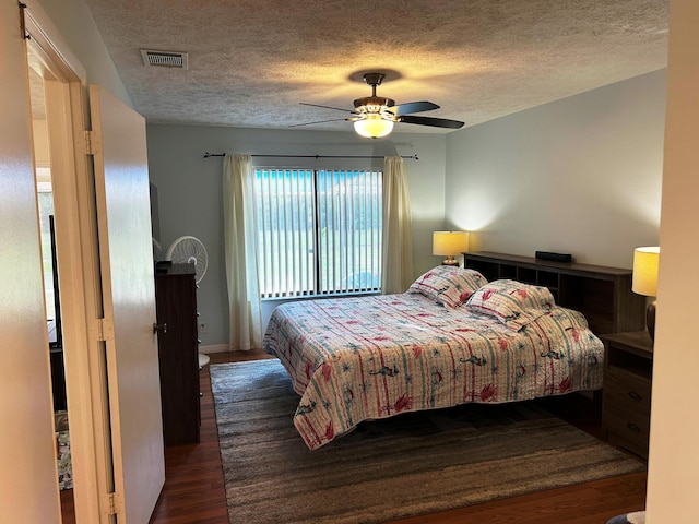 bedroom with dark hardwood / wood-style flooring, ceiling fan, and a textured ceiling