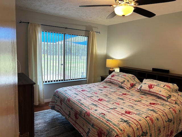 bedroom featuring ceiling fan, dark hardwood / wood-style floors, multiple windows, and a textured ceiling