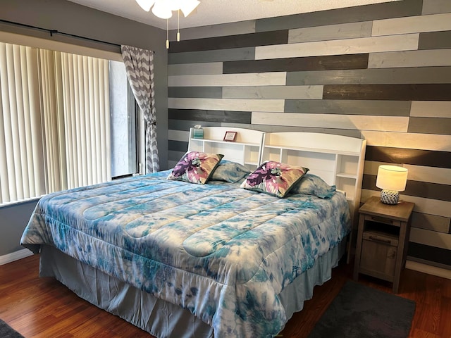 bedroom with dark wood-type flooring, a textured ceiling, and wood walls