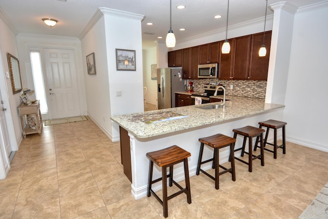 kitchen featuring light stone counters, kitchen peninsula, decorative light fixtures, stainless steel appliances, and sink