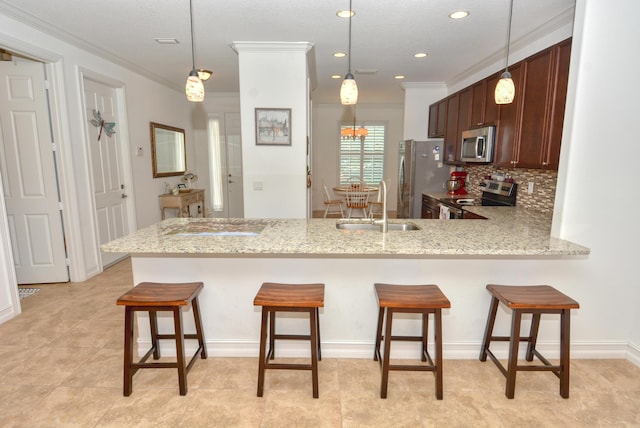 kitchen with a breakfast bar, sink, kitchen peninsula, pendant lighting, and stainless steel appliances