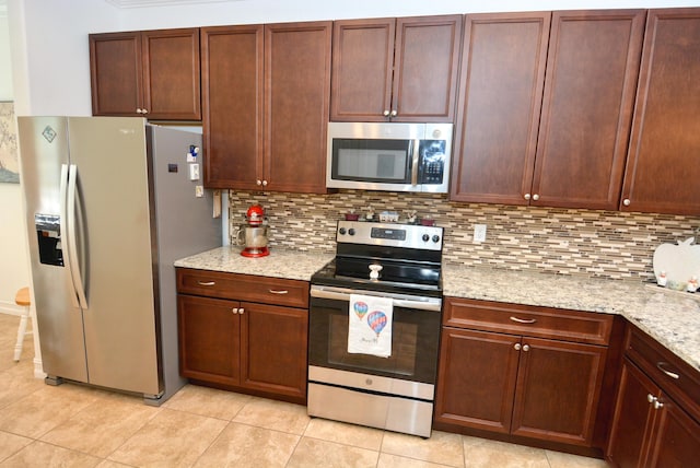 kitchen with tasteful backsplash, stainless steel appliances, light tile patterned flooring, and light stone counters