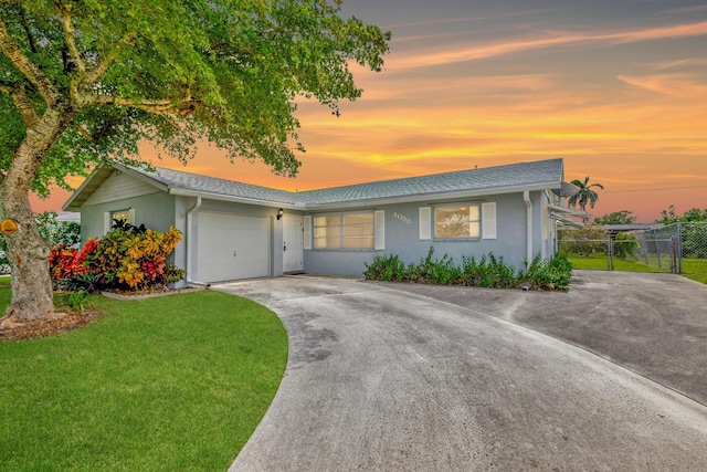 single story home featuring a garage and a lawn