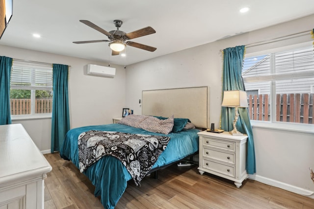 bedroom featuring ceiling fan, a wall mounted AC, and wood-type flooring