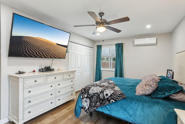 bedroom with a closet, a wall mounted AC, light hardwood / wood-style floors, and ceiling fan